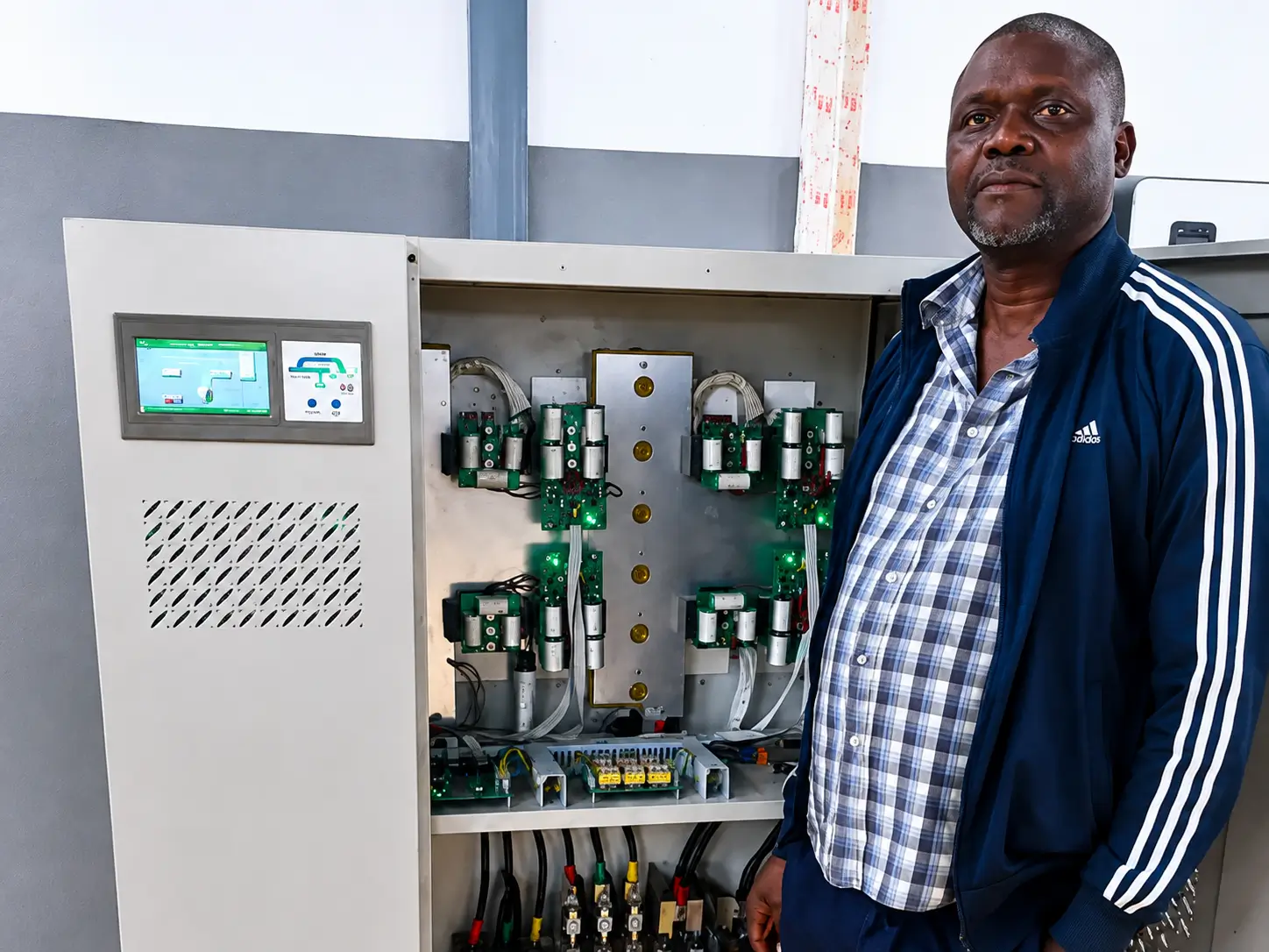 Evans Timburwa beside an open solar inverter panel in Chimoio, Mozambique
